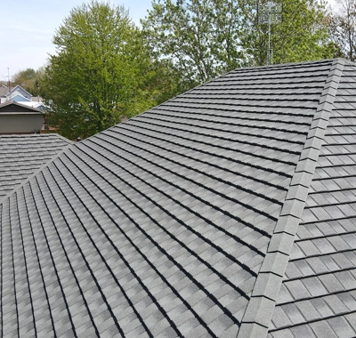 Gray asphalt shingle roof on residential building under clear sky.