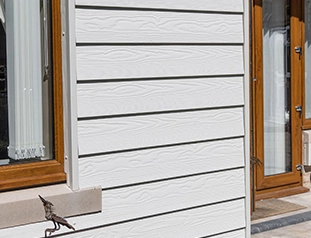 White siding on a house exterior with a window and decorative elements.